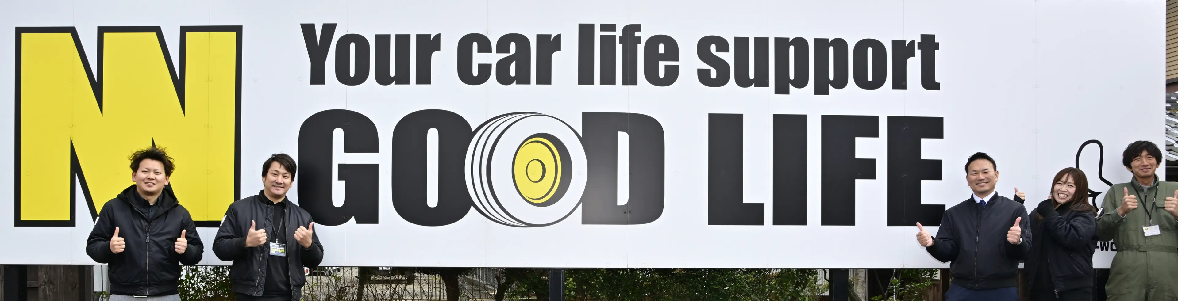 スタッフが店舗の看板の前で並んでいる集合写真