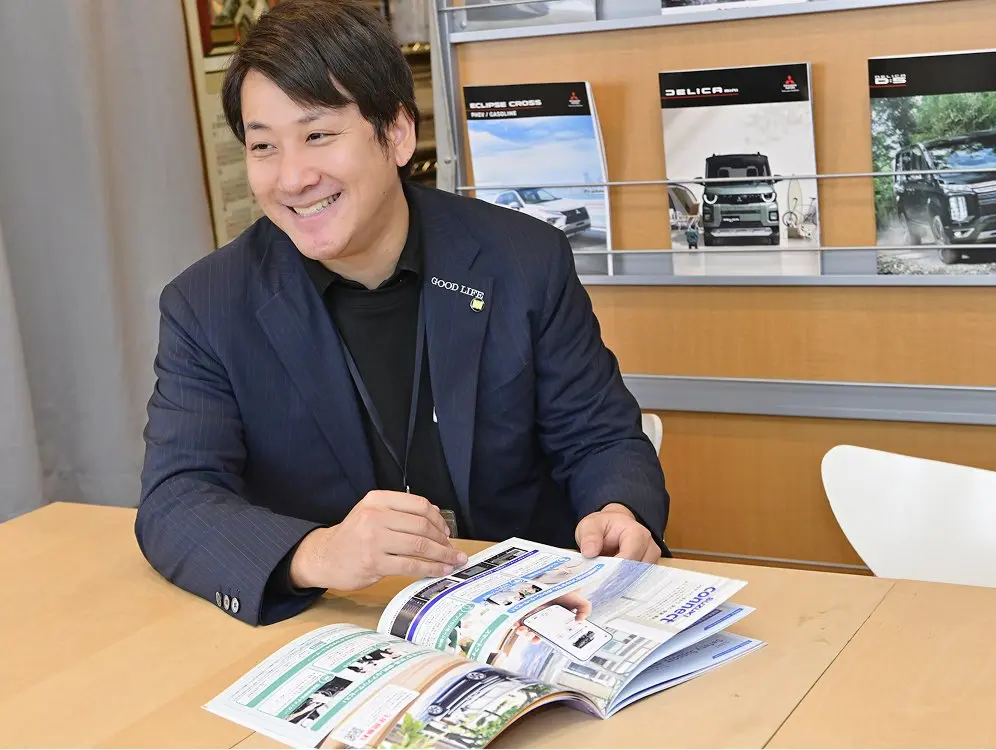 カーディーラーのカタログを見ているスーツ姿のスタッフ