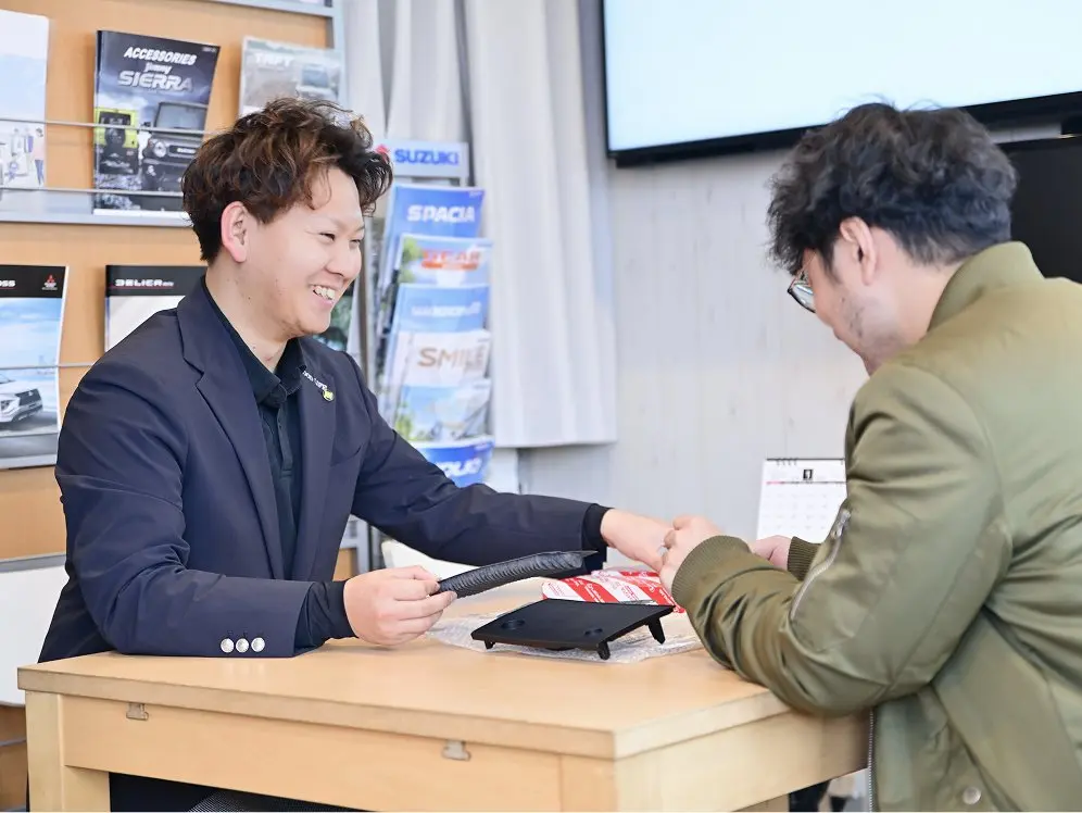 カウンターで顧客と話をするカーディーラーのスタッフ