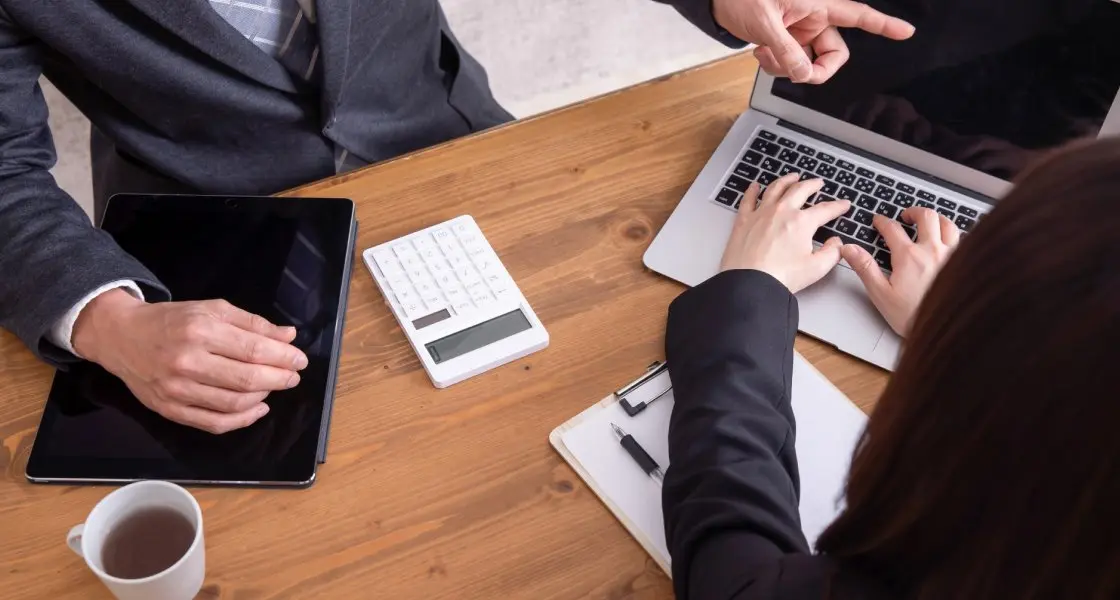 テーブルでノートパソコンを使いながら打ち合わせをする様子