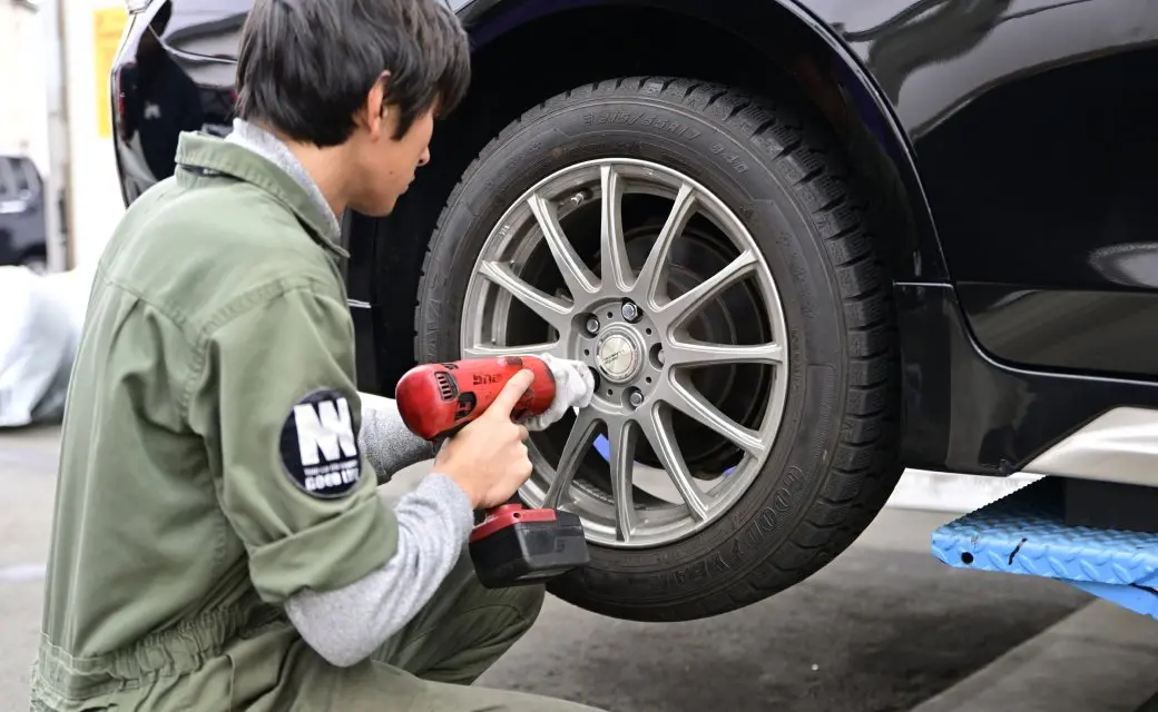 車のタイヤを電動工具で取り付ける整備士