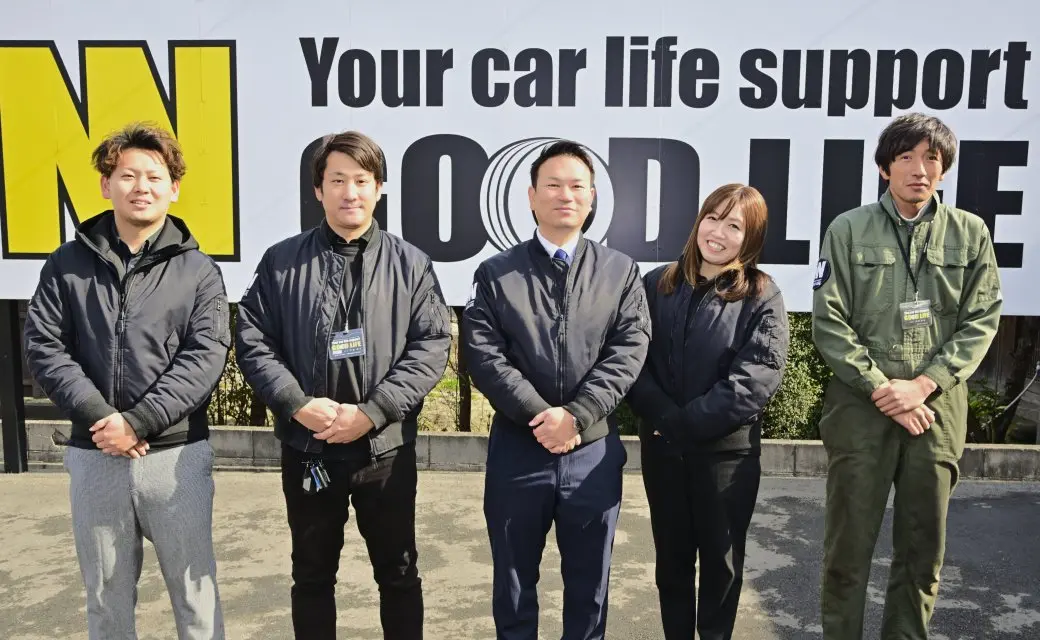 スタッフが店舗の看板の前で並んでいる集合写真