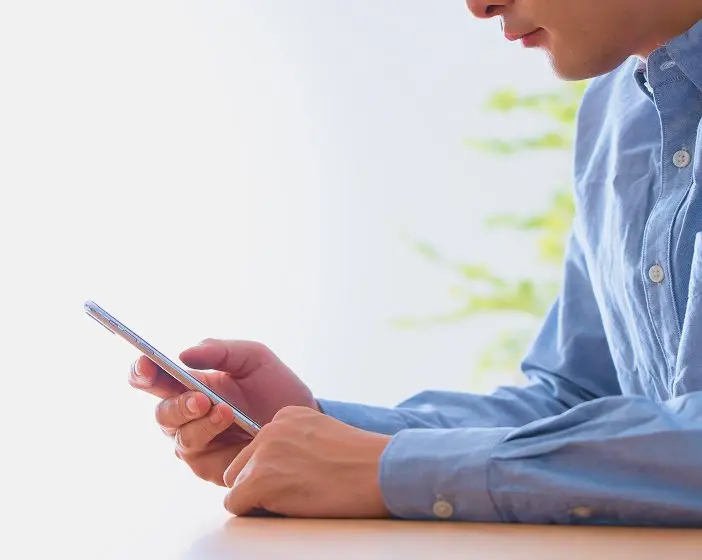 スマートフォンを操作する男性の手元。