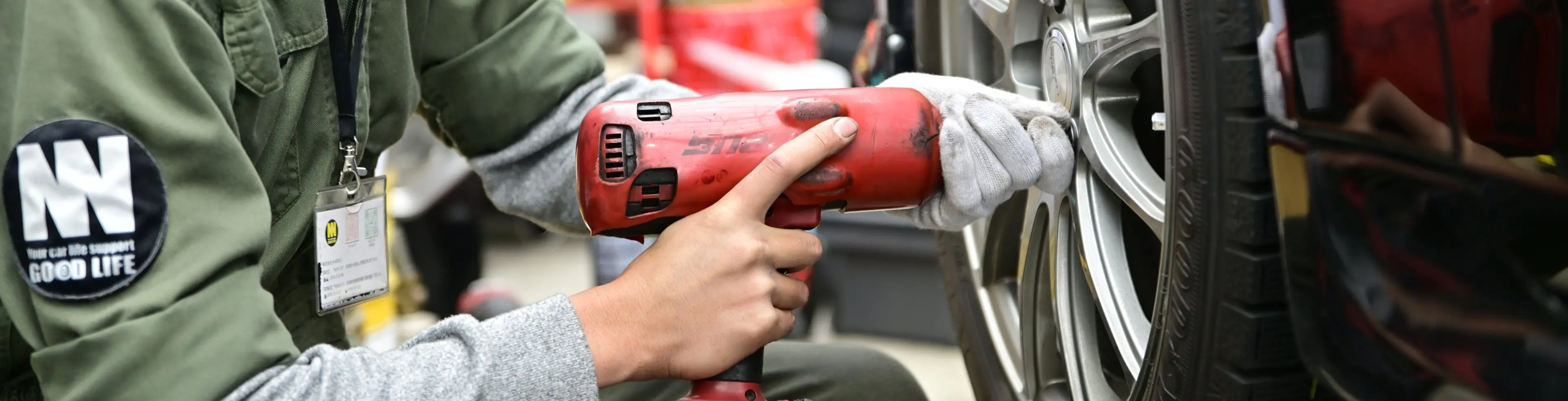 車のタイヤを電動工具で整備する作業員