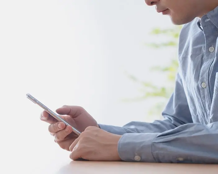 スマートフォンを操作する男性の手元。